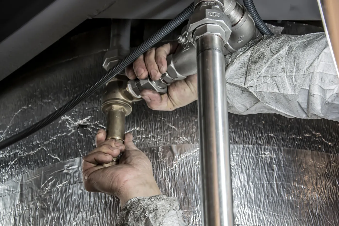 Technician assembling threaded steel gas pipe fittings.