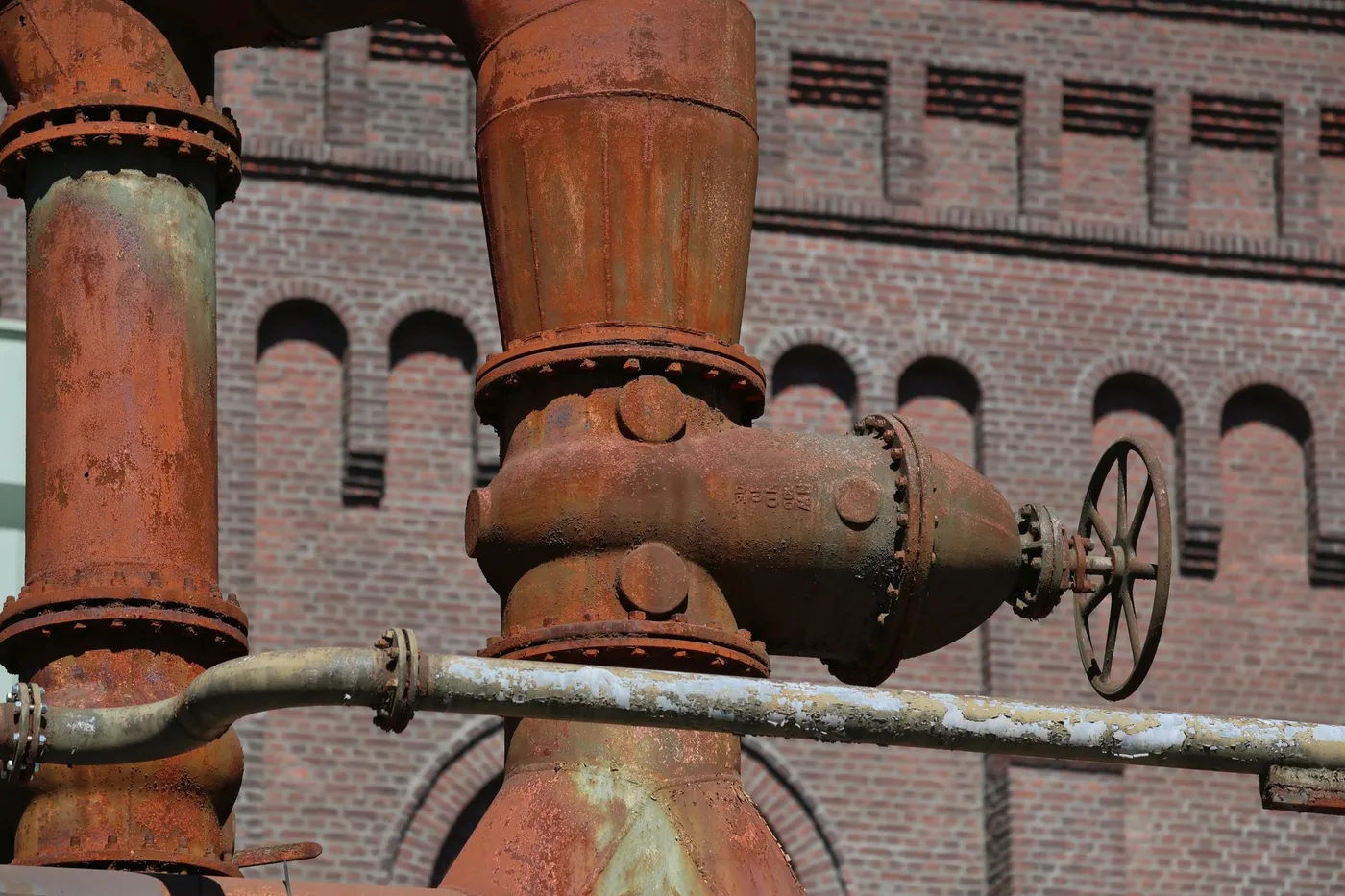 Close-up of a gas water heater control valve and a corroded supply fitting.